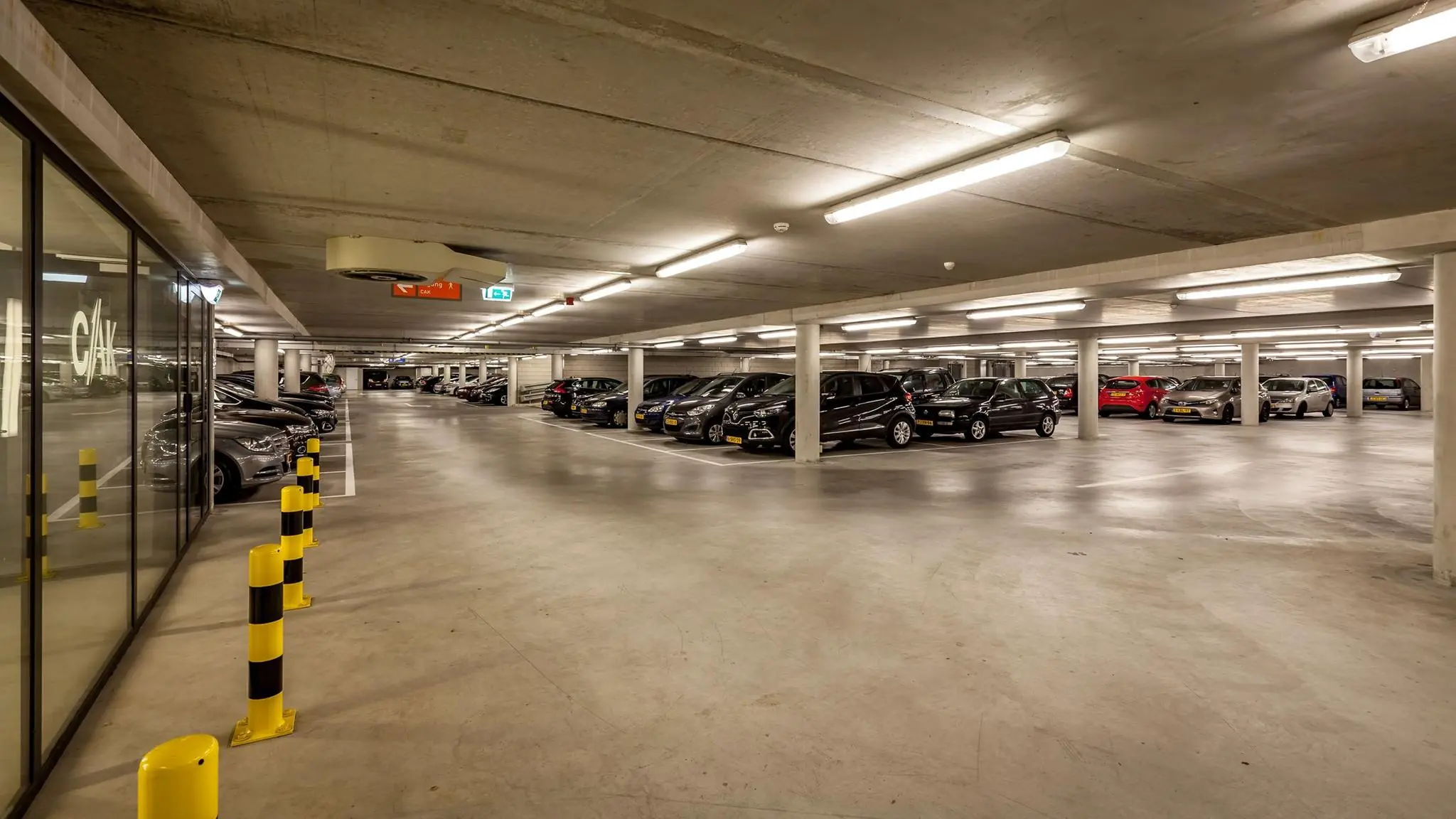 Ondergrondse parkeergarage aan de Prinses Beatrixlaan met geparkeerde auto's en heldere verlichting.